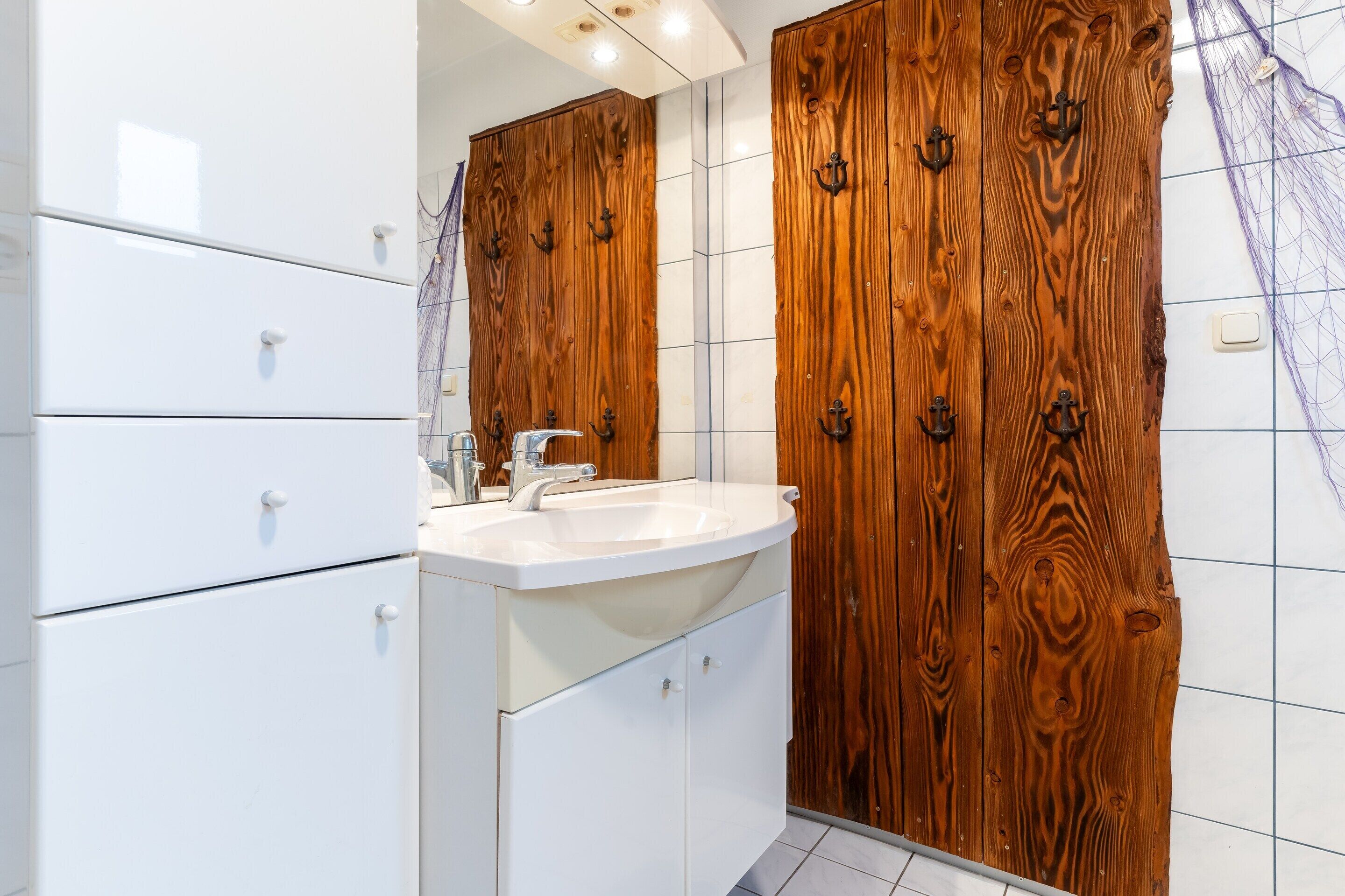 Une salle de bain avec un lavabo blanc, un meuble-lavabo en bois et un miroir.