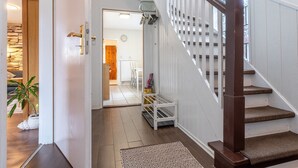 A staircase with wooden steps and a metal banister, leading to a room with a white door and a stone wall. - Ferienwohnung in Busum (Büsum)