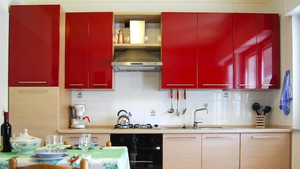 Una cocina con armarios rojos, una cafetera, un hervidor y un lavavajillas.