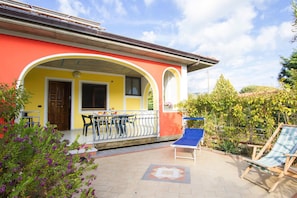A yellow building with a covered patio area, outdoor seating, and a garden. - Apartment in Cilento Near Sandy Beach (Ascea)