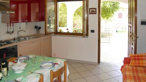 Una cocina con una mesa para dos, una ventana con vistas a la vegetación y una puerta que da al exterior.