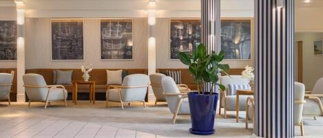 En hotellobby med en sittgrupp, en stor blå blomkruka och inramade konstverk på väggarna.
