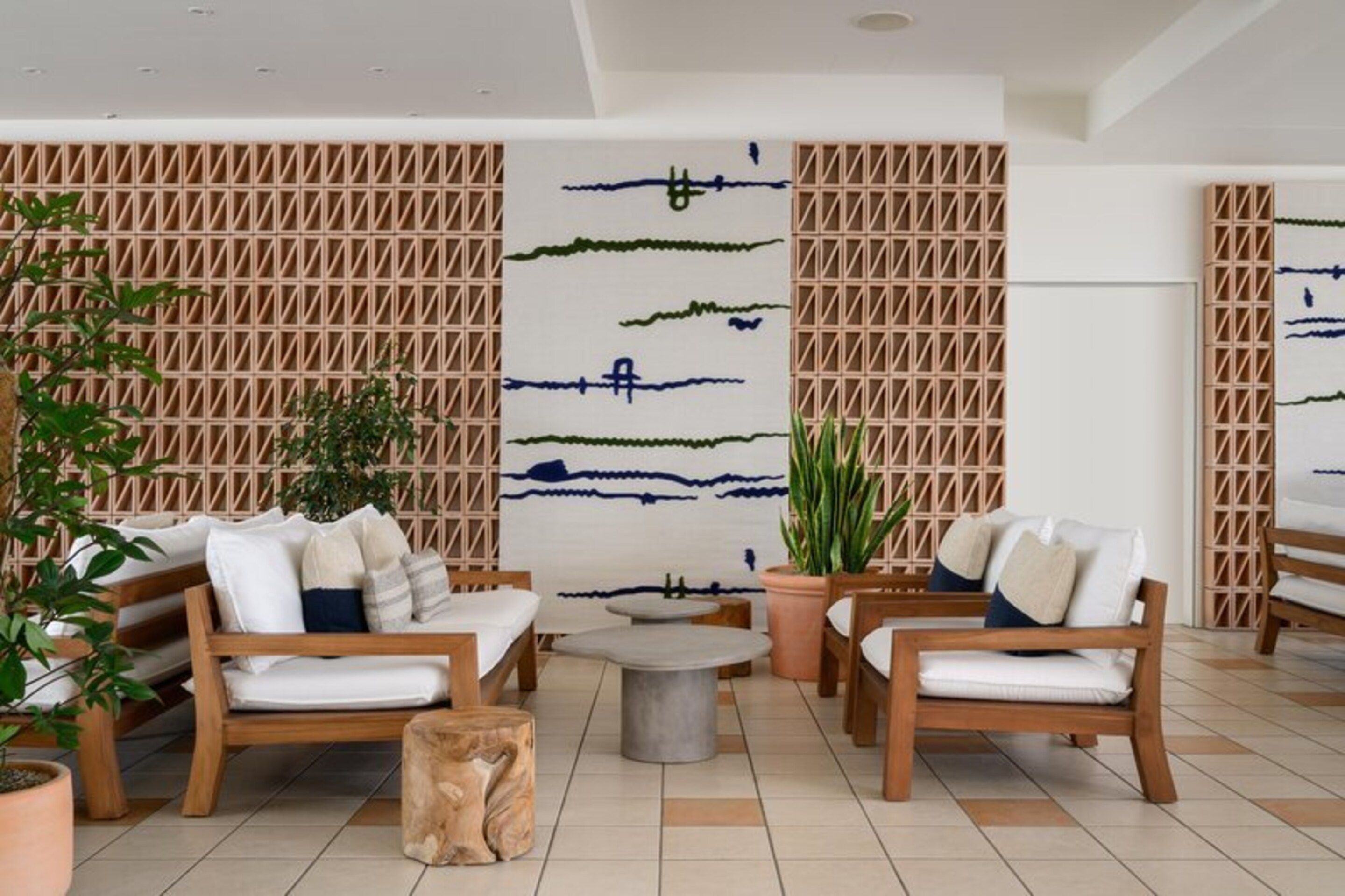 A modern lounge area with wooden furniture, a central round table, and decorative wall panels.