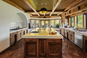 Una cocina amplia con una isla central, armarios de madera y ventanas grandes.