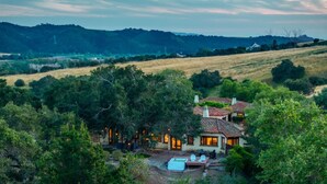 A large house with a swimming pool, surrounded by trees and hills.