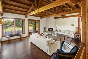 Un amplio salón con chimenea, ventanas grandes y techo de madera.