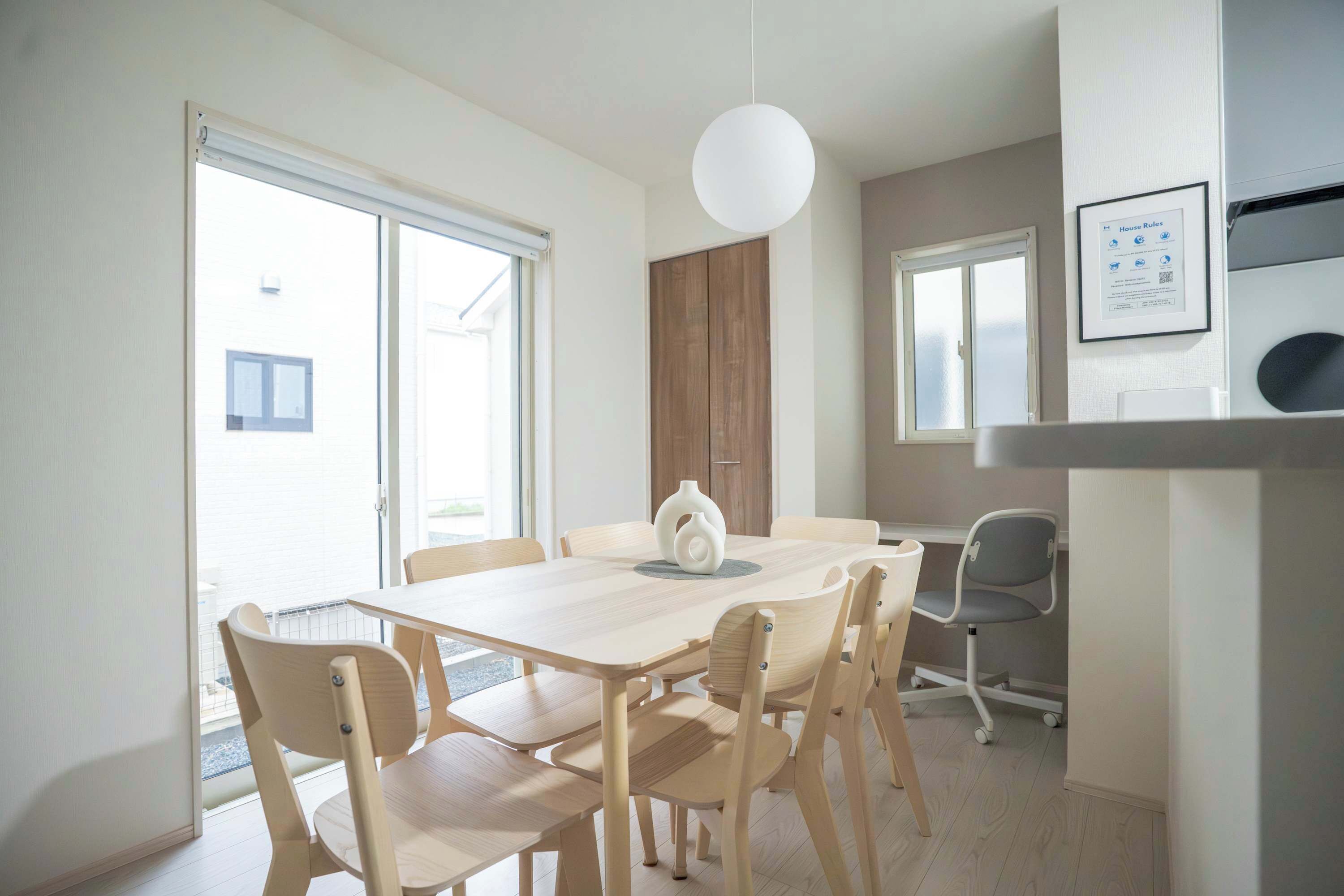 A modern dining area with a wooden table and chairs, a pendant light, and a view of the outside.