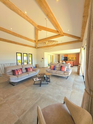 A spacious living area with two sofas, a coffee table, and a dining area in the background.