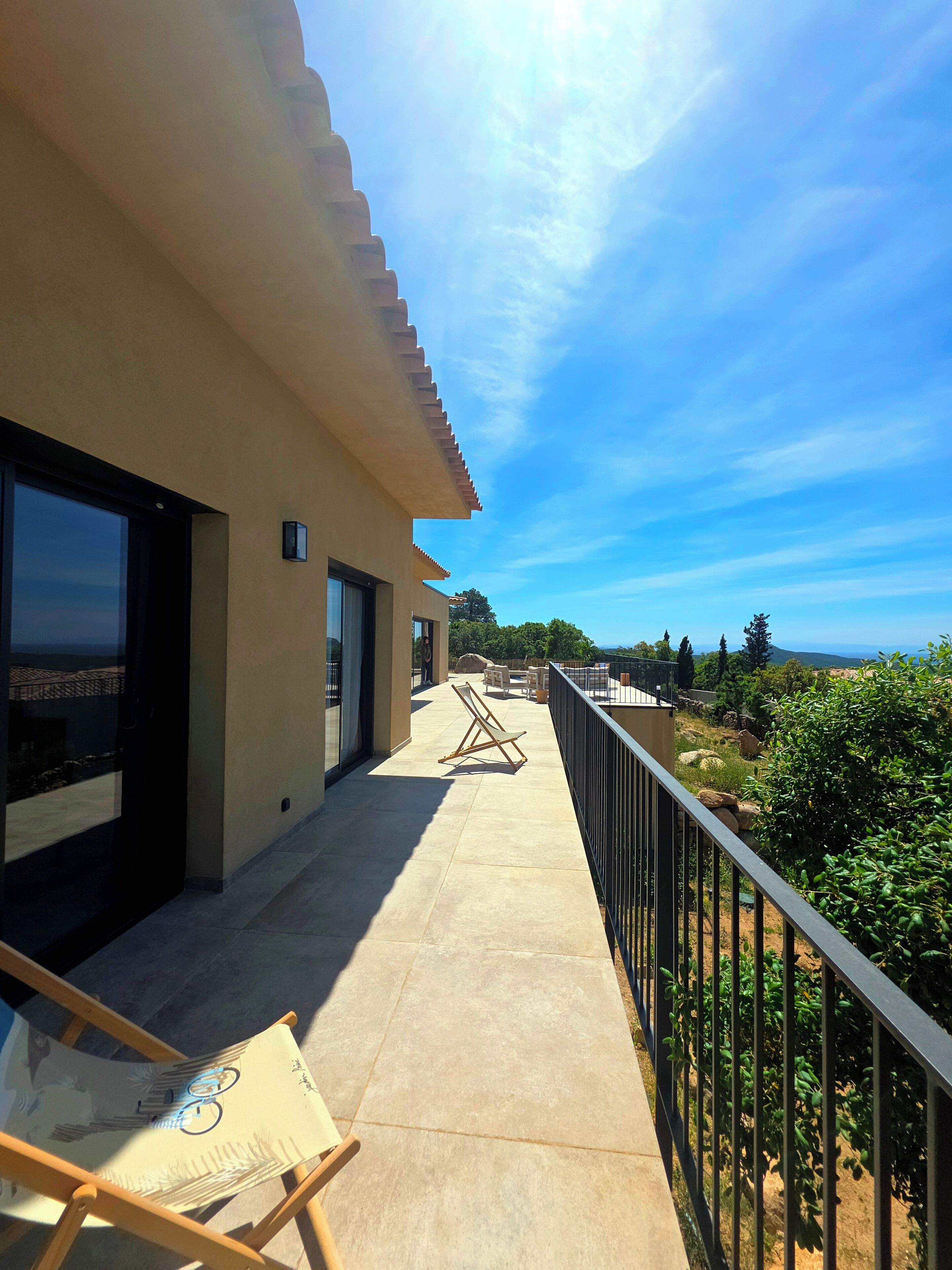 A balcony with a view of the landscape, a chair, and a table.