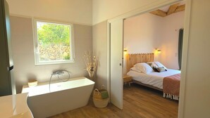 A modern bathroom with a freestanding bathtub, a window, and a wooden floor. - Villa with pool, sea view, Corse-du-Sud (Monacia-d'Aullène)