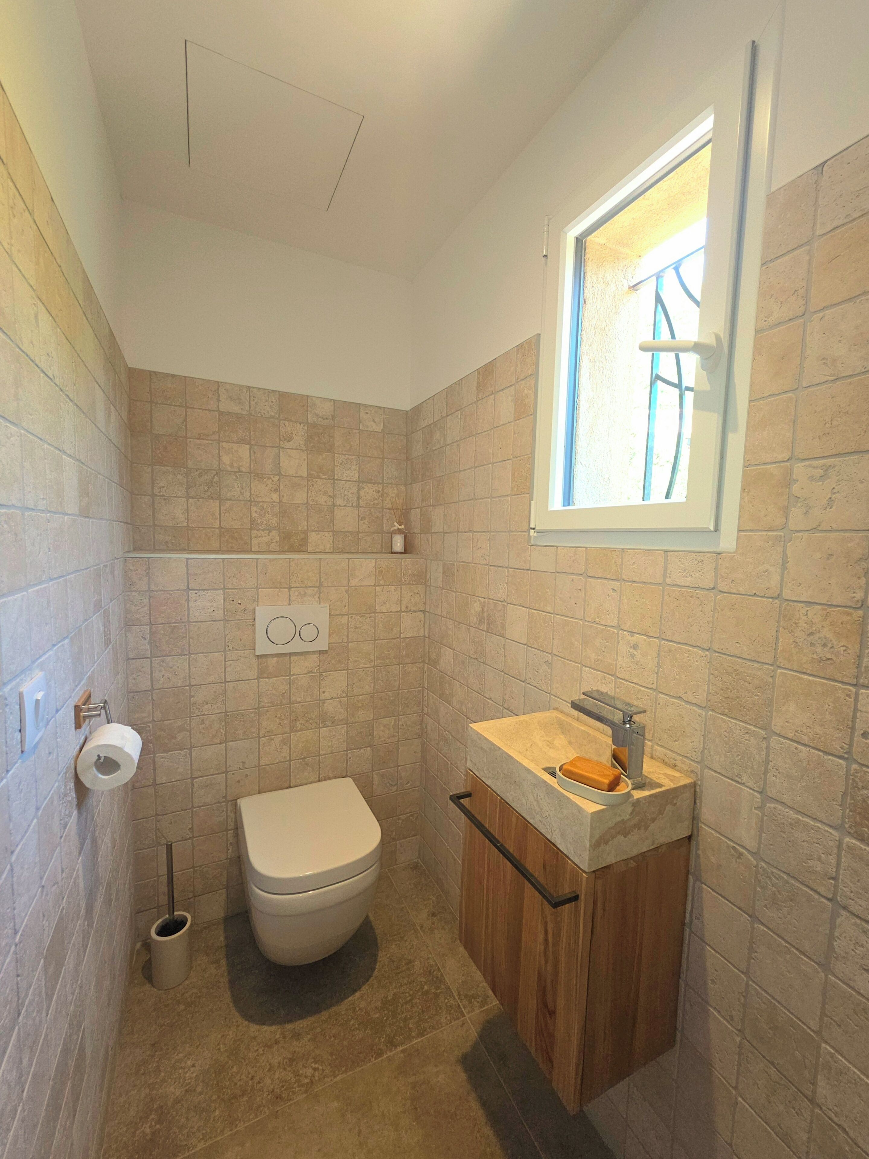A small bathroom with a toilet, sink, and window.
