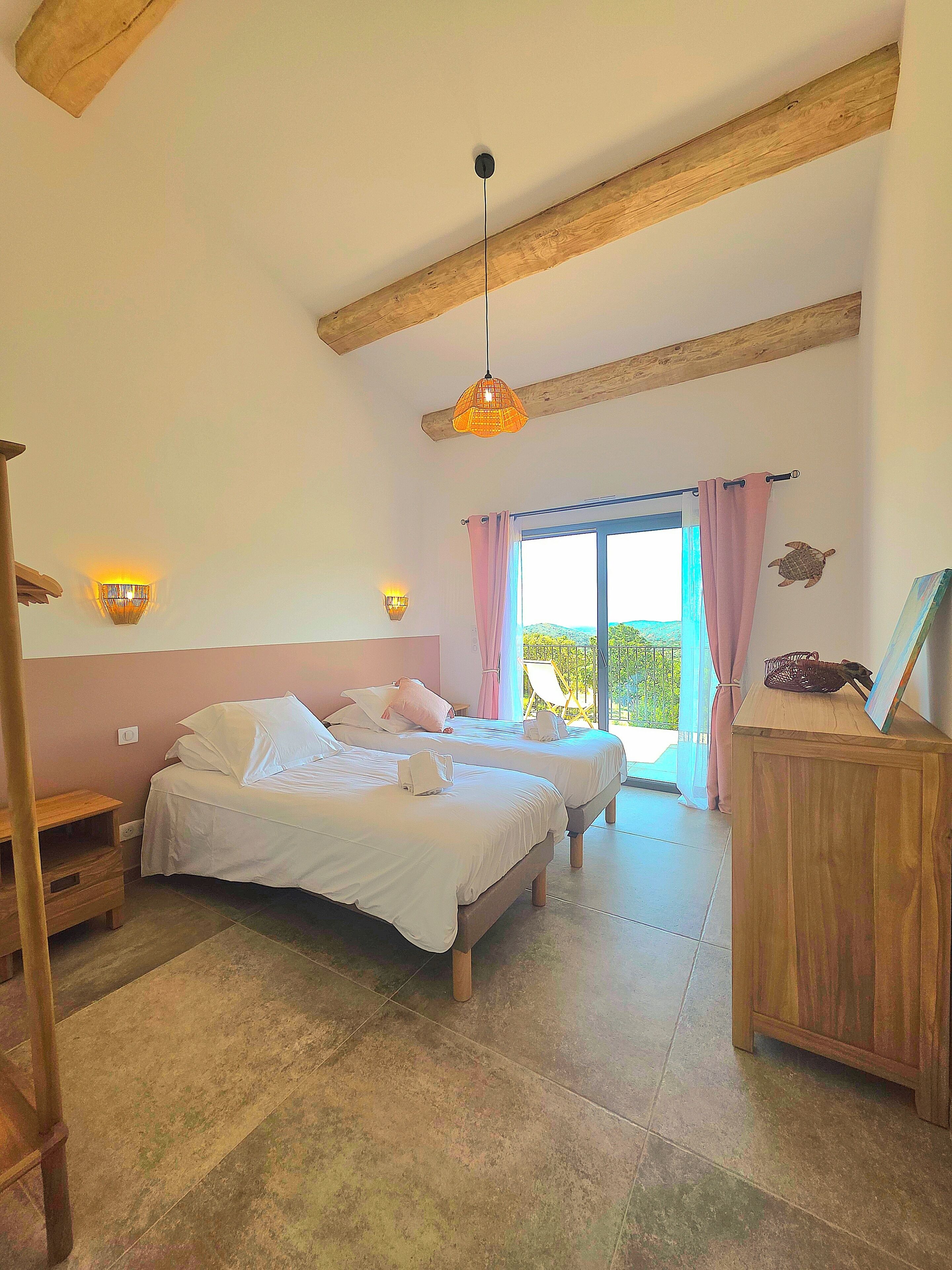 A room with two beds, a wooden ceiling, a wooden cabinet, and a view through a window.