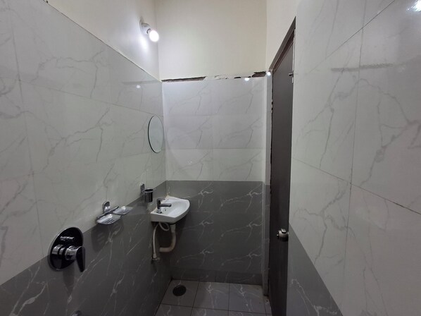 A bathroom with a sink, mirror, and shower area.