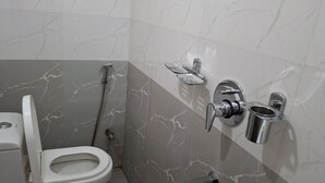 Un bagno con un WC, una doccia e un lavandino con rubinetto.