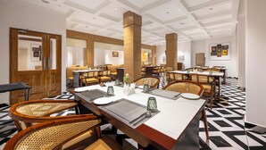 A hotel dining area with multiple tables set for dining, wooden chairs, and a geometric patterned floor. - HOTEL MOUNTAIN MIRAGE (Kumharsain)