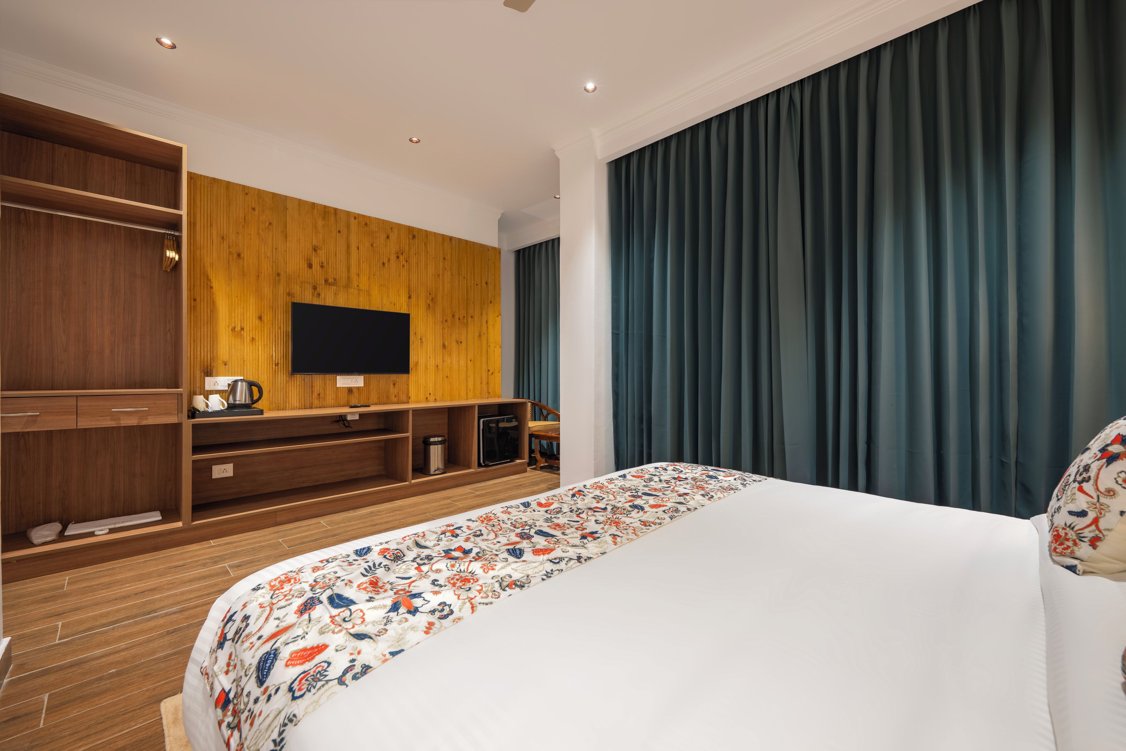 Een hotelkamer met een groot bed, houten paneelwand, een ingebouwde televisie en een kledingkast.