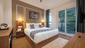 A bedroom with a large bed, bedside lamps, a ceiling fan, a painting on the wall, and a view of the outdoors through a sliding glass door. - HOTEL MOUNTAIN MIRAGE (Kumharsain)