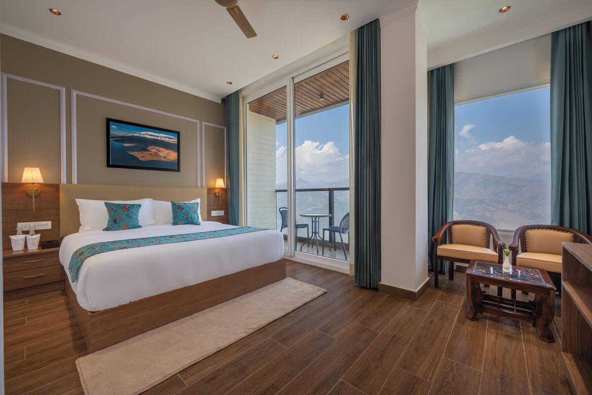 Une chambre d’hôtel avec un grand lit, un balcon avec vue, un bureau et une chaise.