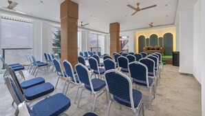 A conference room with rows of chairs, ceiling fans, and a view through large windows. - HOTEL MOUNTAIN MIRAGE (Kumharsain)