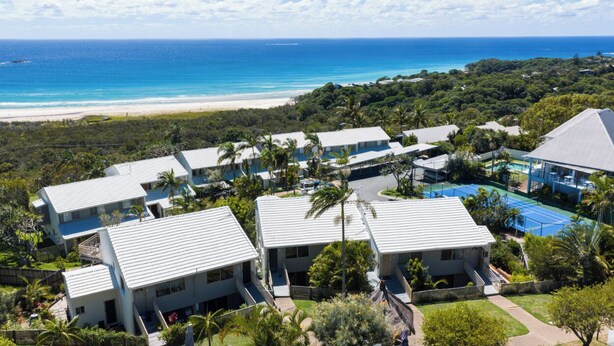 A resort with multiple buildings, a pool, and a beach view.