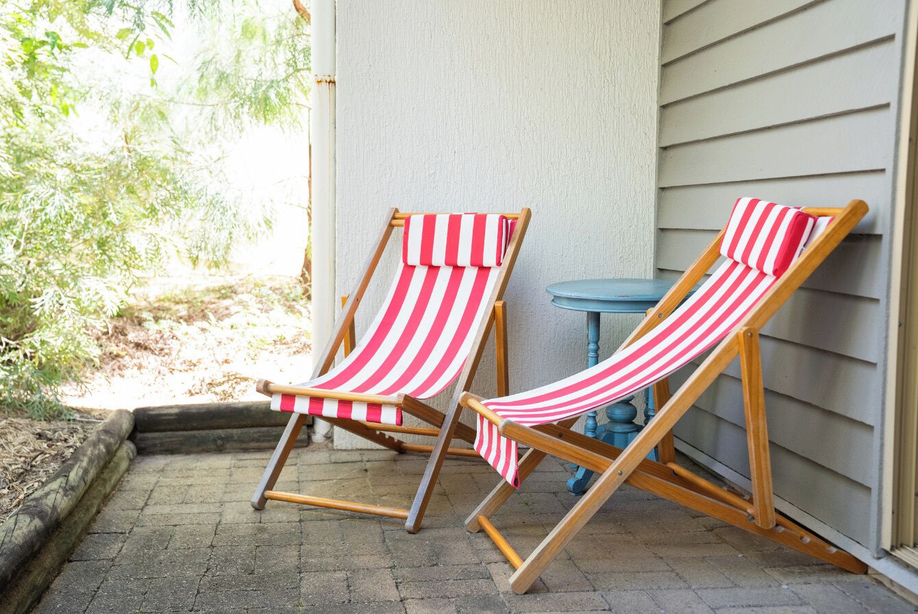 Two striped beach chairs outside a building with a brick patio.