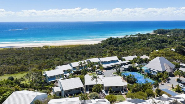 A resort with multiple buildings, a pool, and a beach view.