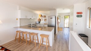 A modern kitchen with a central island, bar stools, and a refrigerator.