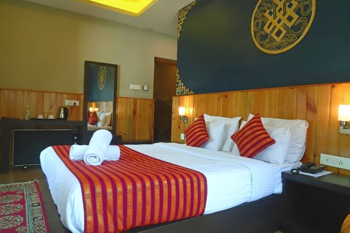 Una habitación de hotel con una cama, un escritorio, un teléfono y una pared con un emblema decorativo.