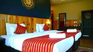 Habitación de hotel con cabecera de madera, dos camas con sábanas blancas y colchas a rayas rojas, un espejo grande y un adorno en la pared.