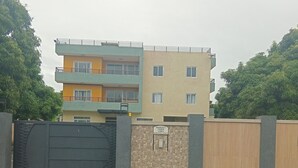 Edificio residencial de varios pisos con entrada protegida, muro de piedra y un cartel que indica vigilancia.