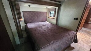 Une chambre à coucher avec un lit, une tête de lit, une fenêtre et une porte.