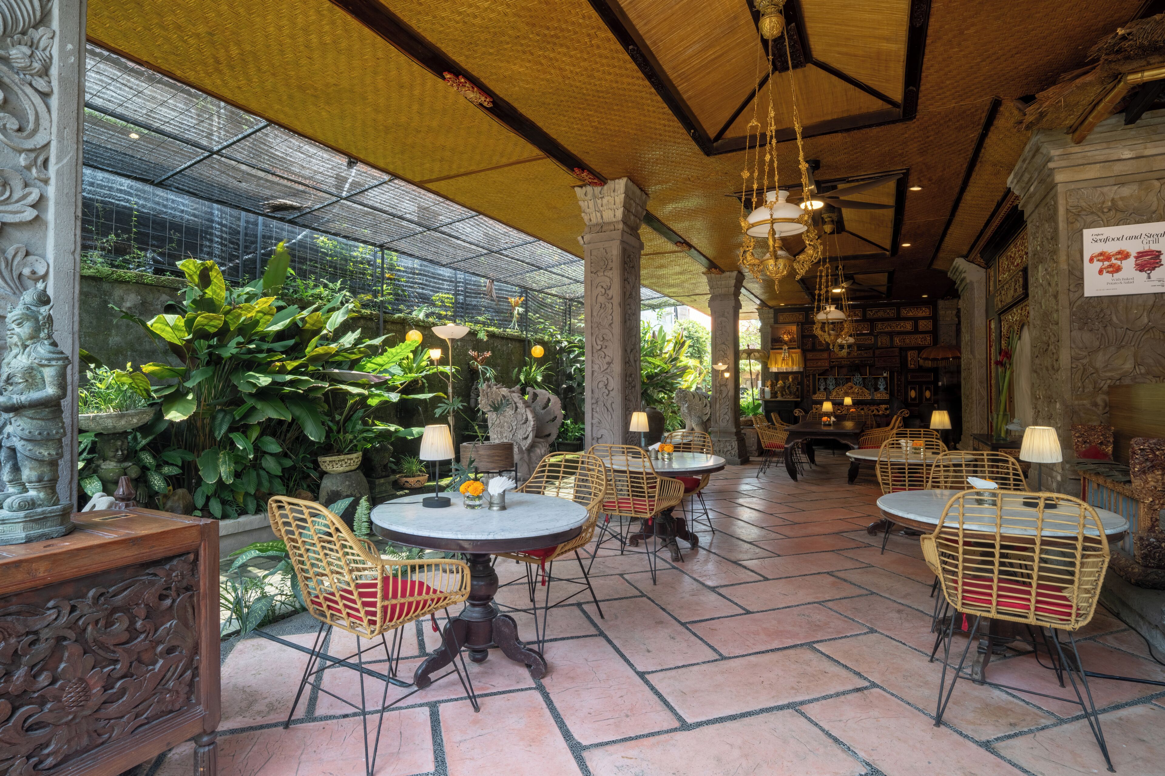 A restaurant with outdoor seating, tables, chairs, and hanging lights.