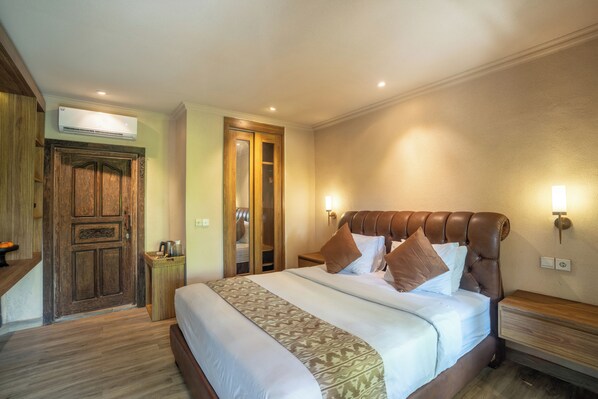 A bedroom with a large bed, wooden wardrobe, and a small bedside table.