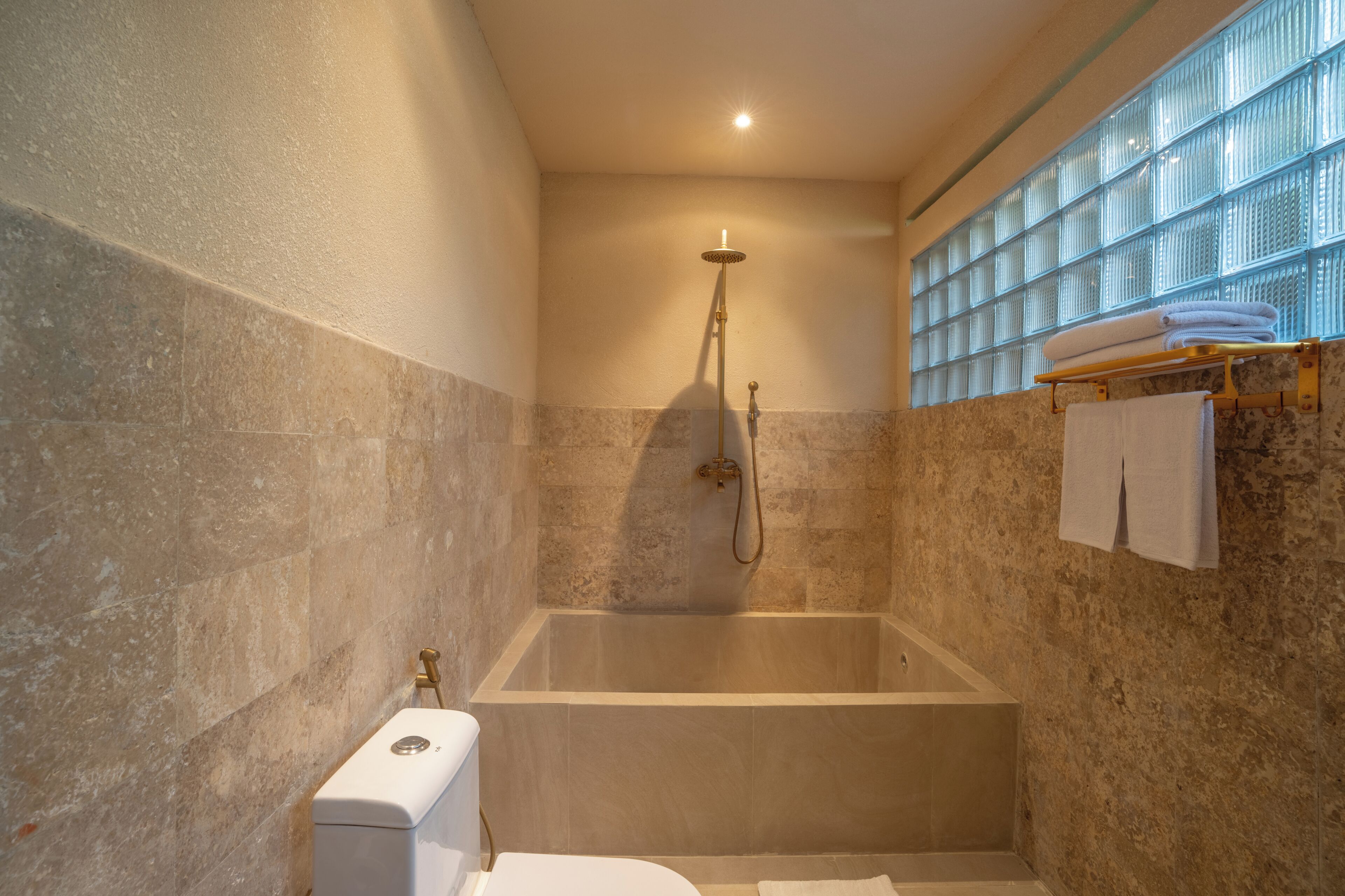 A bathroom with a bathtub, a toilet, and a towel rack with towels.