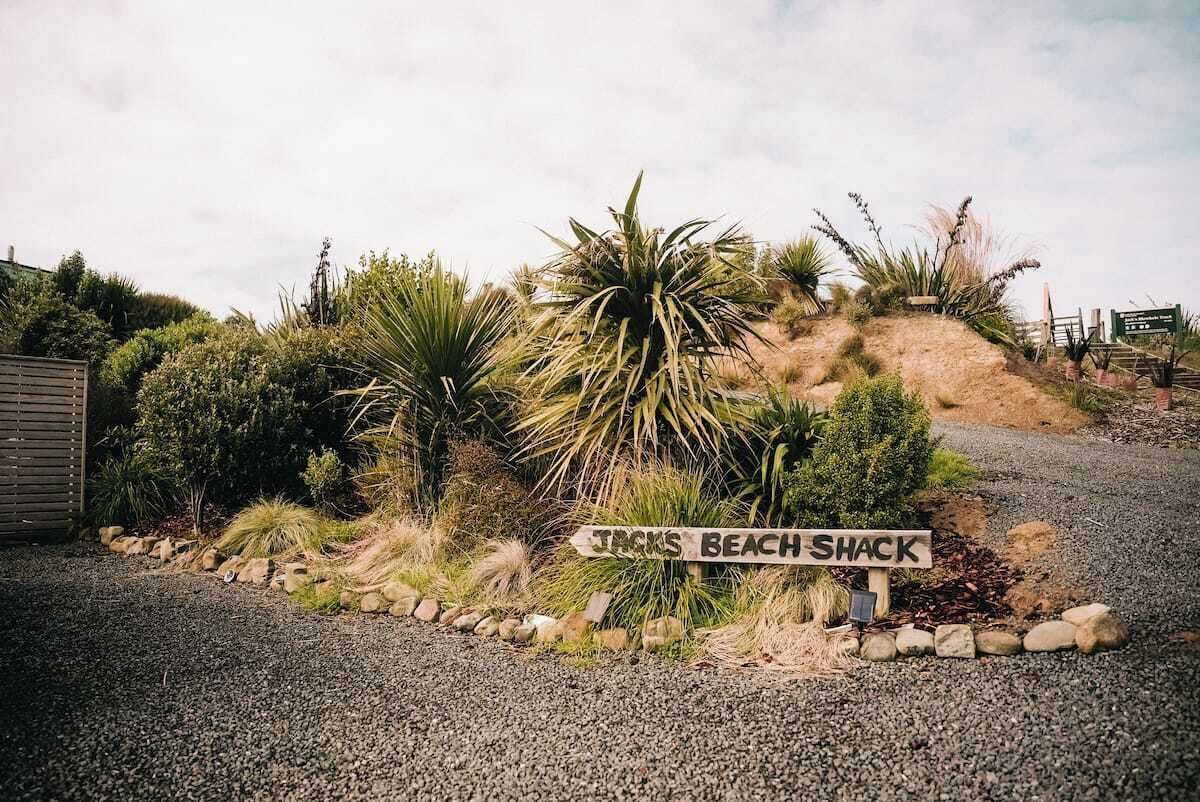 A gravel path leading to a sign that reads 'TRICKS BEACH SHACK.'