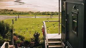 Vista desde una habitación con ventana que da a una playa, una zona verde y una extensión de agua.
