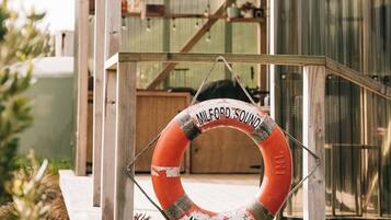 Eine Holzhütte mit einem Rettungsring, auf dem 'MELFORD SOUND NEW ZEALAND' steht, der an einem Seil hängt.