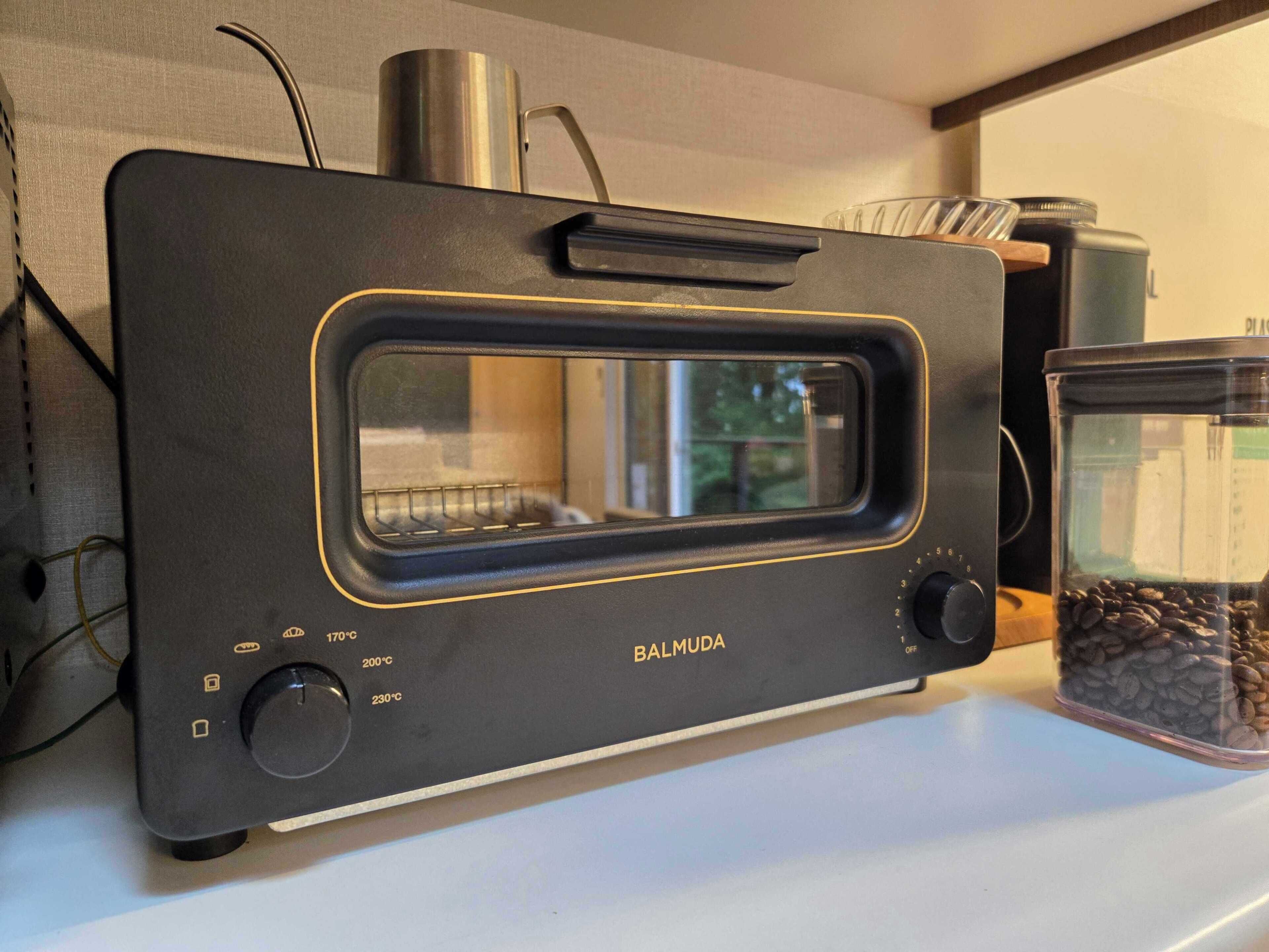 A kitchen with a toaster oven, a coffee maker, and a glass container with coffee beans.