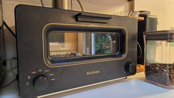 A kitchen with a toaster oven, a coffee maker, and a glass container with coffee beans.