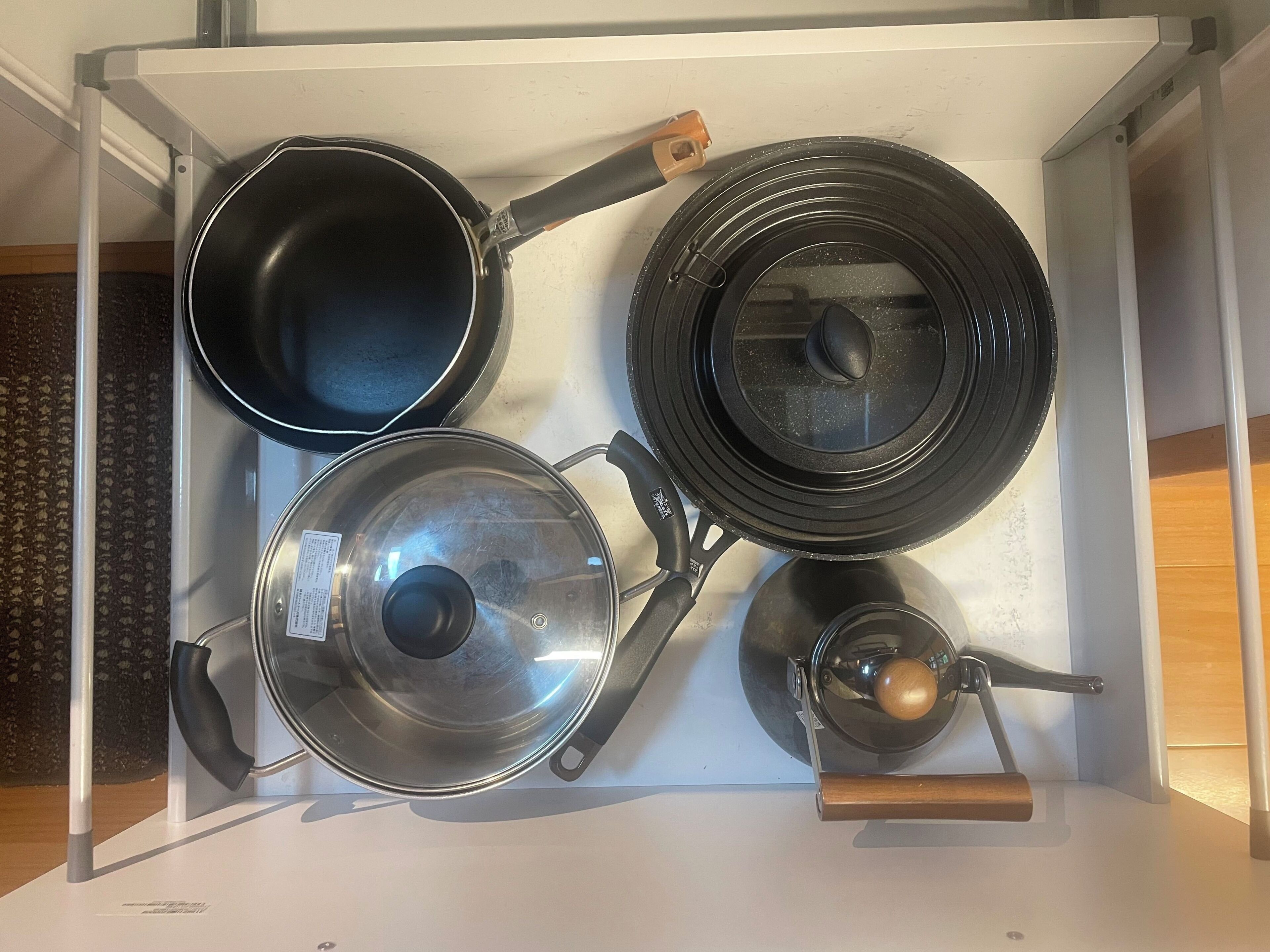 Un cajón de cocina con diferentes ollas y sartenes.