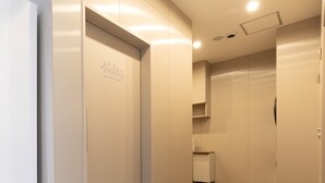 Un pasillo con un cartel que indica baños universales, un cubo de basura y una puerta a la derecha.
