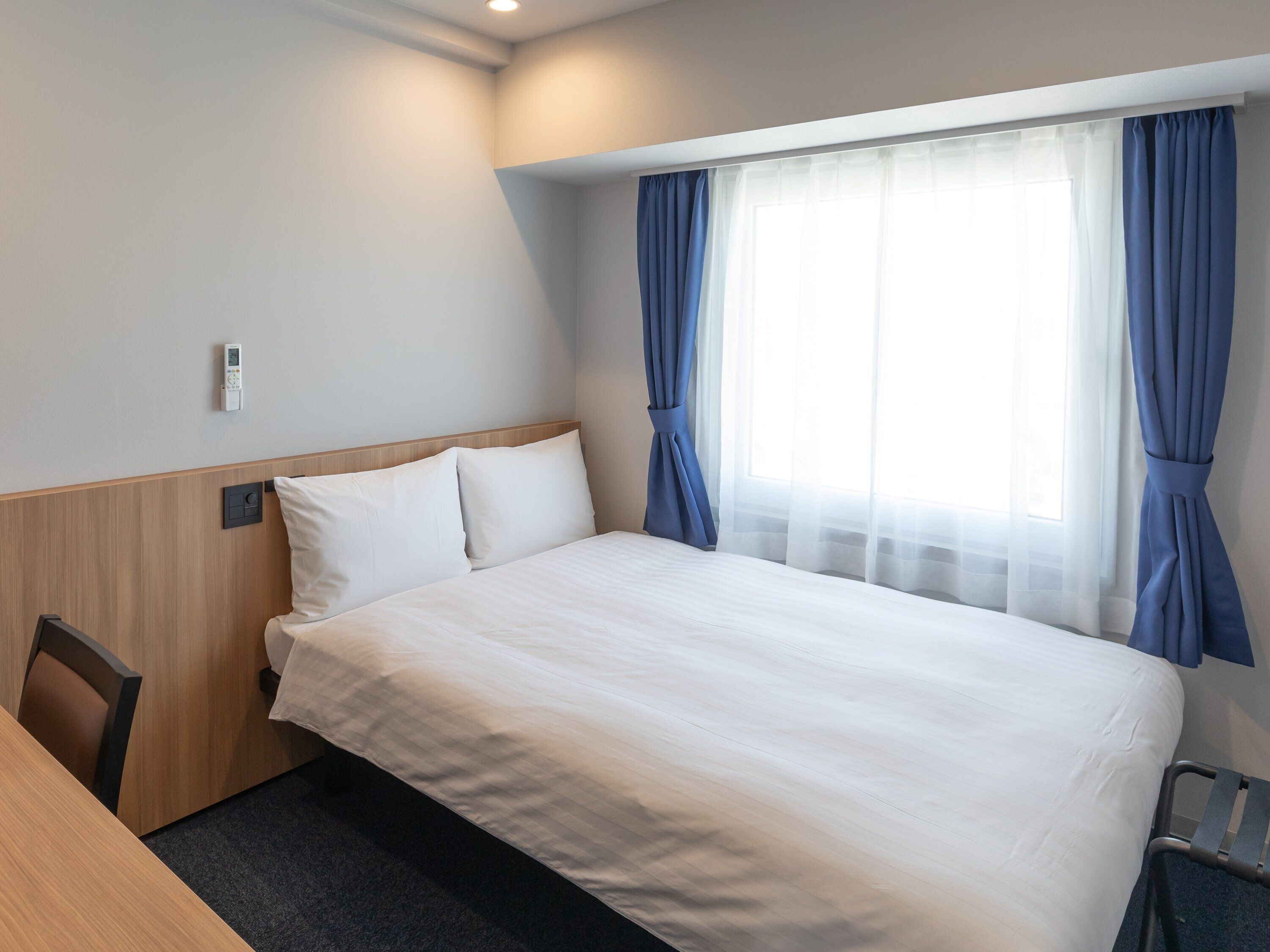 A hotel room with a bed, a desk, and a chair.