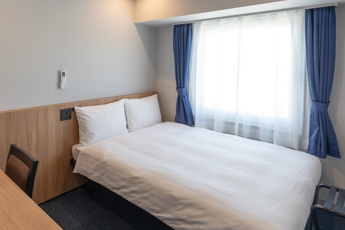A hotel room with a bed, a desk, and a chair.