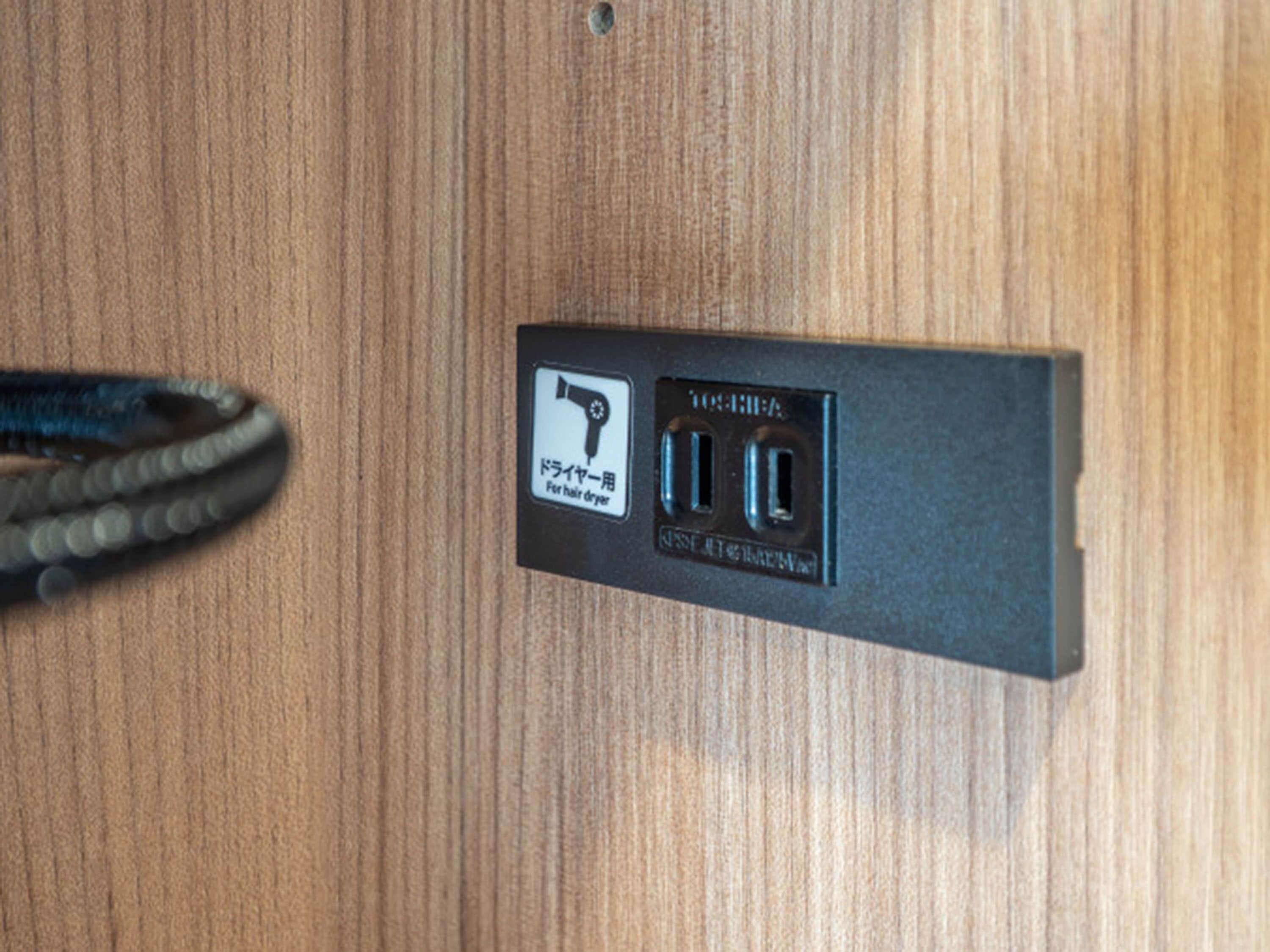 A wall-mounted electrical outlet with a hairdryer symbol and two USB ports.