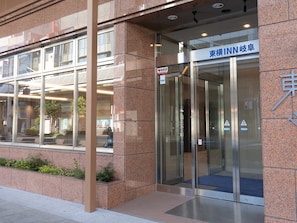 A modern building entrance with a glass door, a sign indicating an AED, and a blue sign with Japanese characters. - Toyoko Inn Gifu (Gifu)