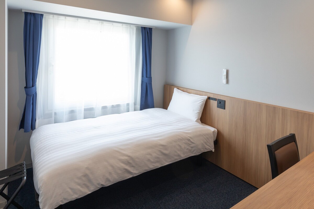A hotel room with a bed, a desk, and a chair.