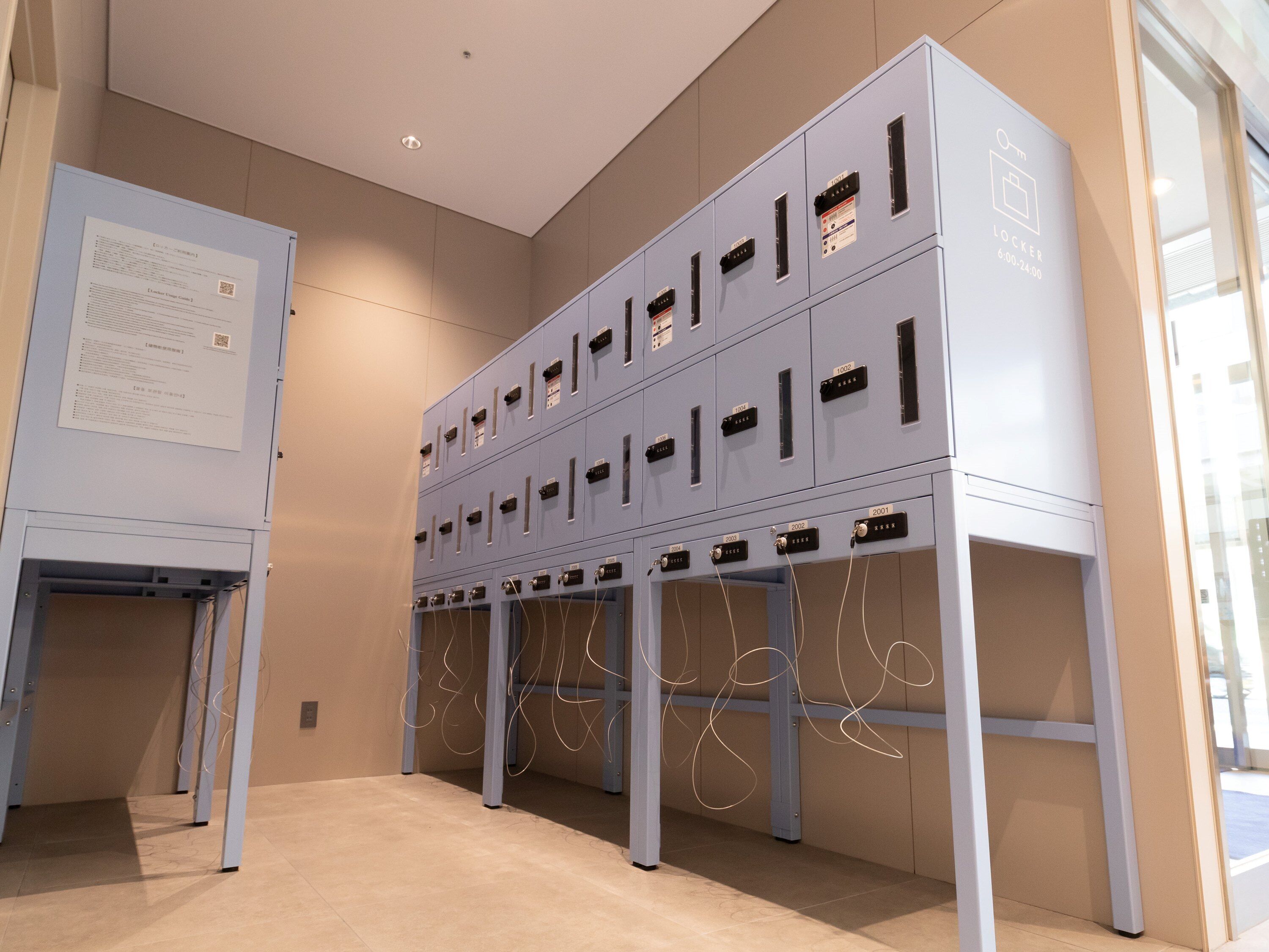 A row of lockers with numbered compartments, a whiteboard with text, and a glass door reflecting the outside.
