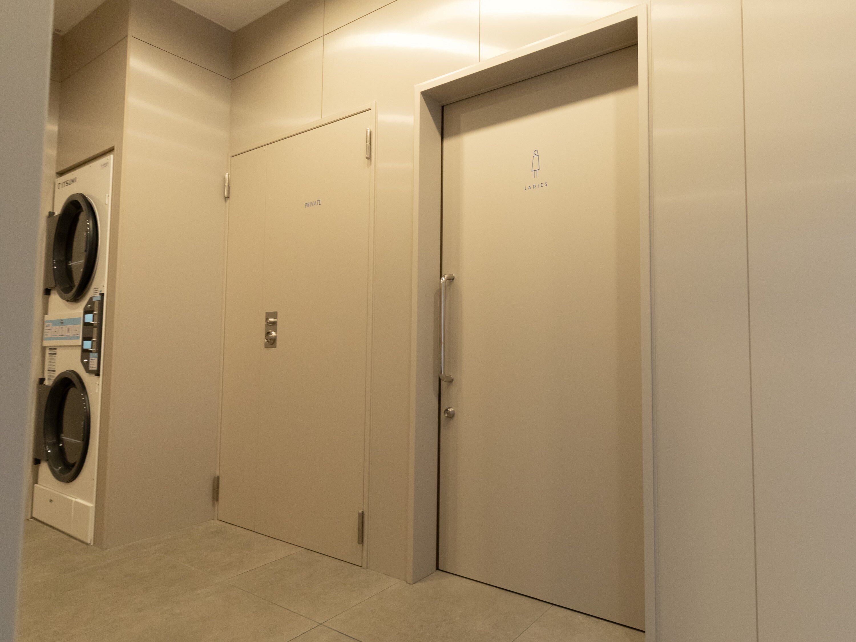 A private elevator with a door marked 'LADIES' and a wall-mounted washer in a hallway.