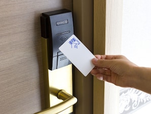 A hand holding a card in front of a digital keycard reader with 'TOYOKO INN' visible.