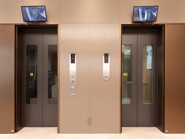 Een paar liftdeuren met een digitaal scherm, een bedieningspaneel met knoppen en een klein scherm boven de deuren.